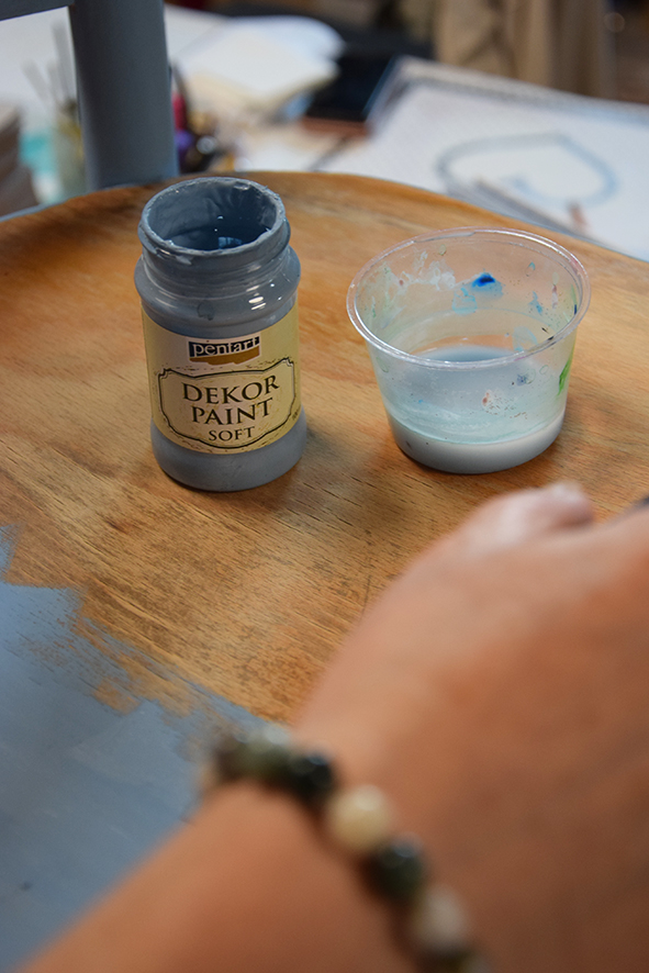 Žena natírá židli modrou Decor paint barvou s pomocí štětce.