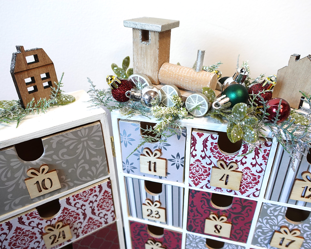 Detail na adventní kalendář v luxusní bordovo-stříbrné kombinaci s dřevěnými ozdobami, umělou jeřabinou a vánočními kuličkami.